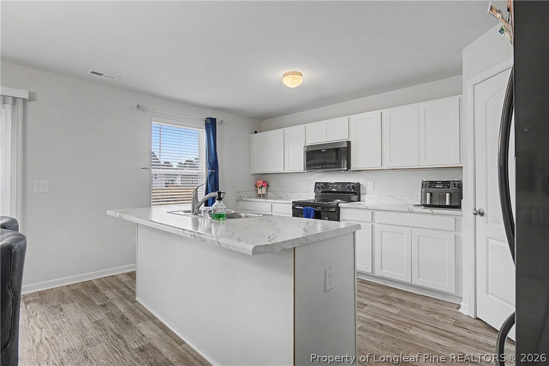 1717 Ennismore Road Hope Mills, NC 28348 - Photo 8 of 33 a kitchen with stainless steel appliances a sink a stove a refrigerator cabinets and a window