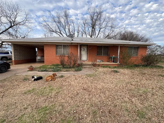a front view of a house with yard and large tree