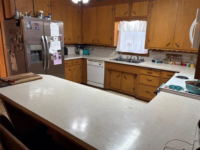 a kitchen with stainless steel appliances granite countertop a sink refrigerator and cabinets