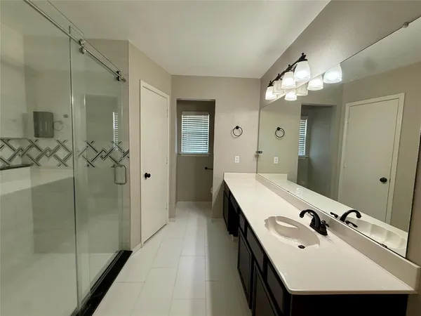 a bathroom with a sink shower and a mirror