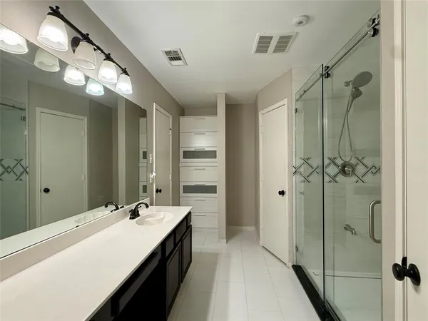 a bathroom with a double vanity sink a large mirror and shower