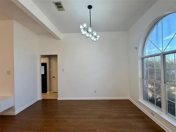 a view of a room with wooden floor chandelier and windows