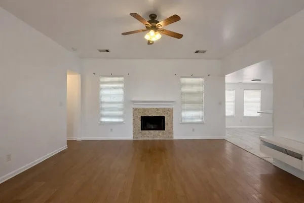 a view of a room with a ceiling fan fireplace and wooden floor