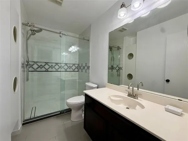 a bathroom with a sink a toilet a mirror and shower