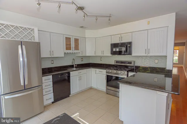 a kitchen with granite countertop a refrigerator stove top oven and sink