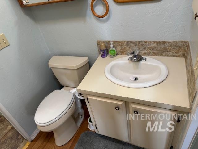 910 Moonglo, Unit 49 Buhl, ID 83316 - Photo 13 of 16 Half bathroom featuring vanity, a textured wall, and wood finished floors