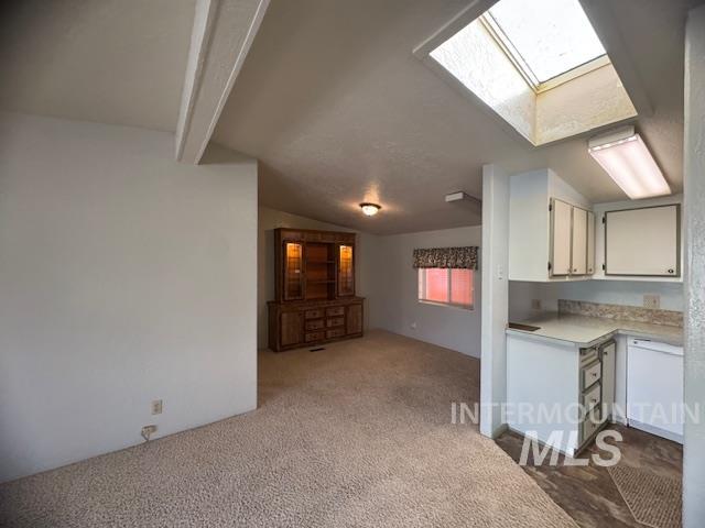 910 Moonglo, Unit 49 Buhl, ID 83316 - Photo 15 of 16 Kitchen with light countertops, vaulted ceiling with beams, a skylight, dark colored carpet, and white cabinets
