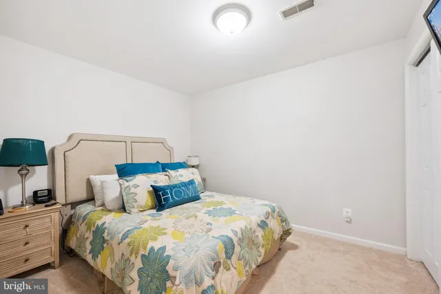 a bedroom with a bed and a lamp on dresser