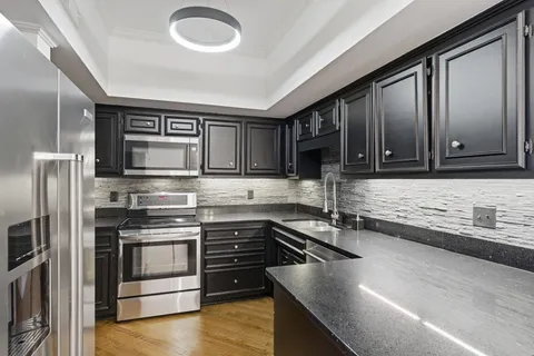 a kitchen with stainless steel appliances granite countertop a stove a sink and a microwave