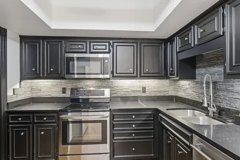 a kitchen with granite countertop a sink cabinets and stainless steel appliances