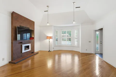 a view of an empty room with wooden floor fireplace and a window