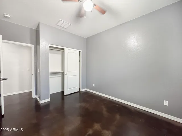 an empty room with a fan & a window