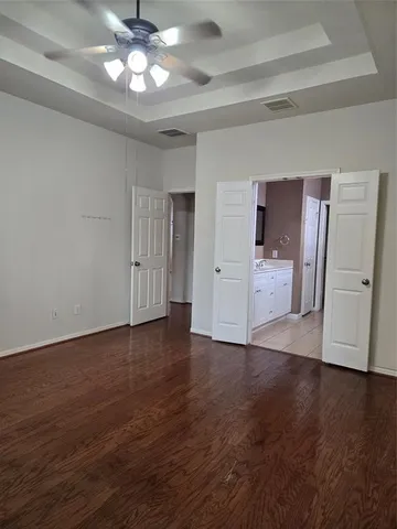 a view of an empty room with wooden floor and a kitchen