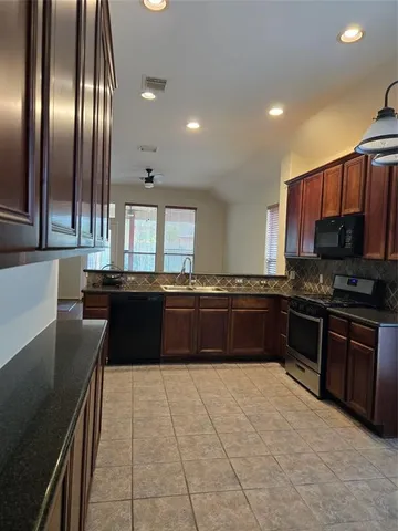 a large kitchen with granite countertop a stove and cabinets