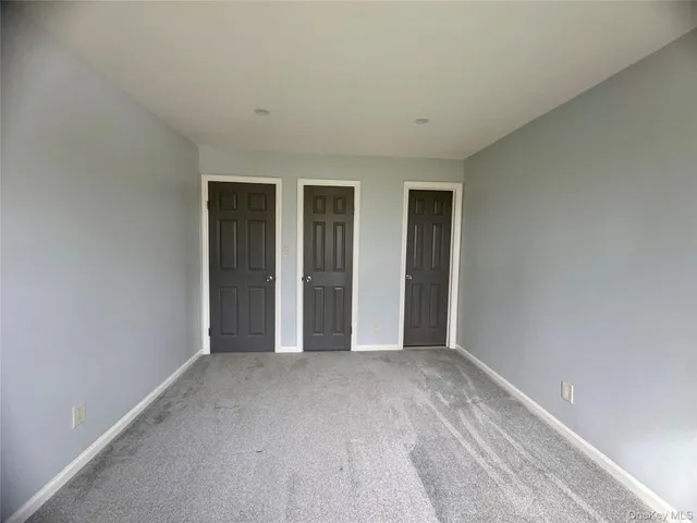 a view of an empty room with wooden floor and closet
