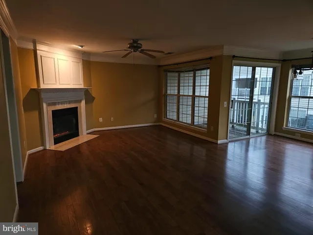 a view of an empty room with wooden floor fireplace and a window