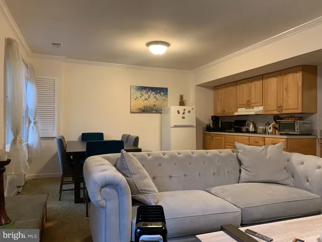 a living room with furniture kitchen view and a window