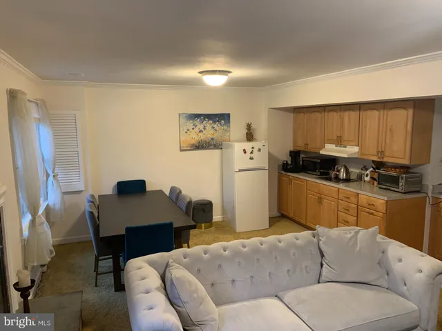 a living room with furniture and a refrigerator