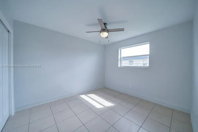 an empty room with windows and ceiling fan