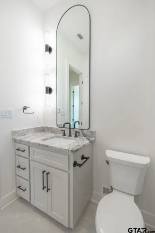a bathroom with a granite countertop toilet sink and mirror