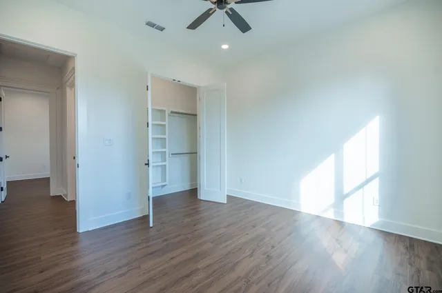 an empty room with wooden floor cabinet and windows