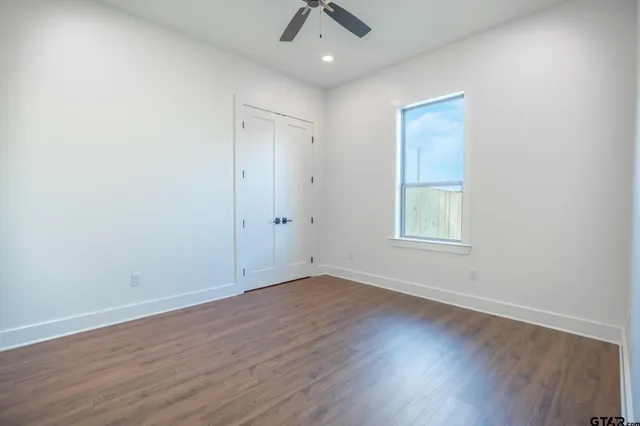 an empty room with a hardwood and ceiling fan