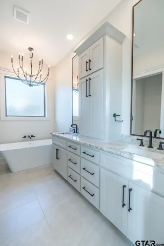 a spacious bathroom with double vanity a mirror a bathtub and double vanity