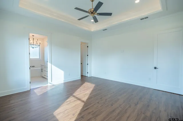 an empty room with wooden floor and a ceiling fan