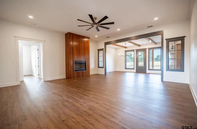 an empty room with wooden floor fan and windows