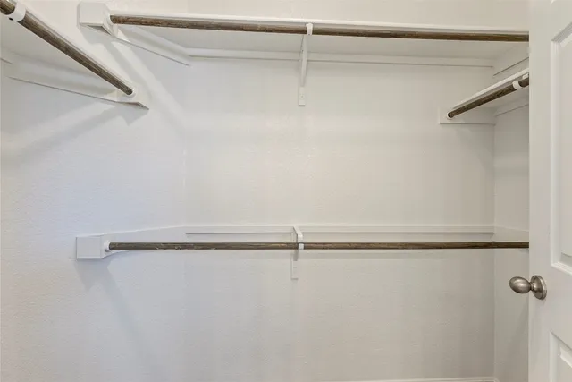 an empty room with closet and a chandelier fan