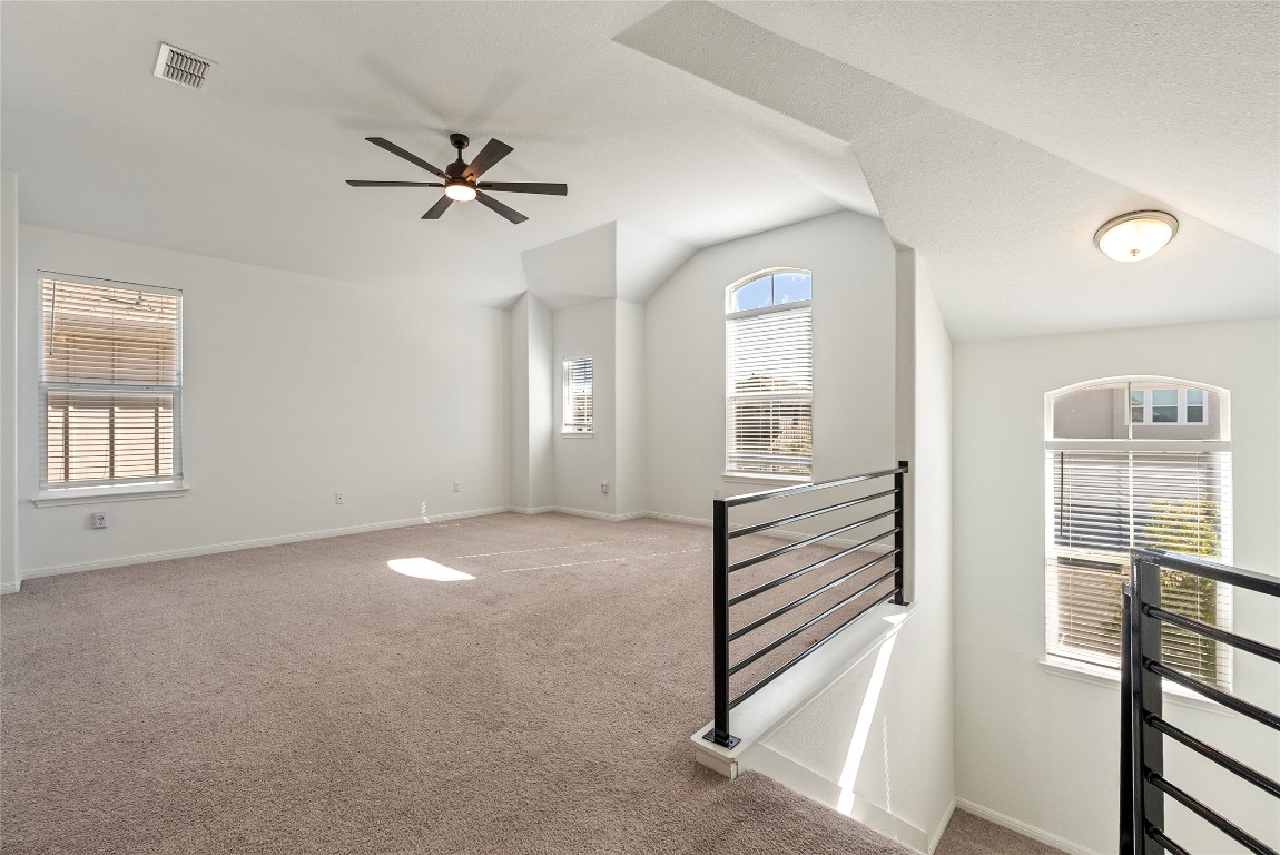 10704 Sentinel Drive Austin, TX 78747 - Photo 11 of 22 Spare room with carpet floors, lofted ceiling, and ceiling fan