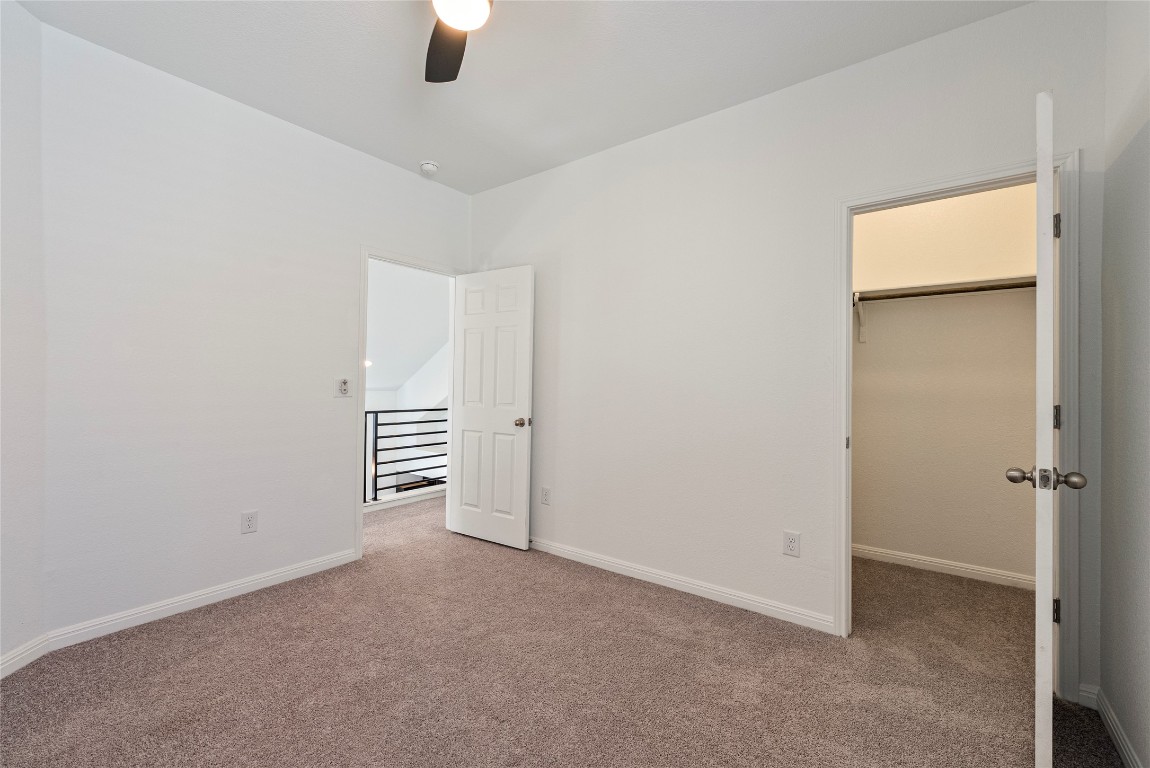 10704 Sentinel Drive Austin, TX 78747 - Photo 14 of 22 Unfurnished bedroom with a spacious closet, carpet, and a ceiling fan