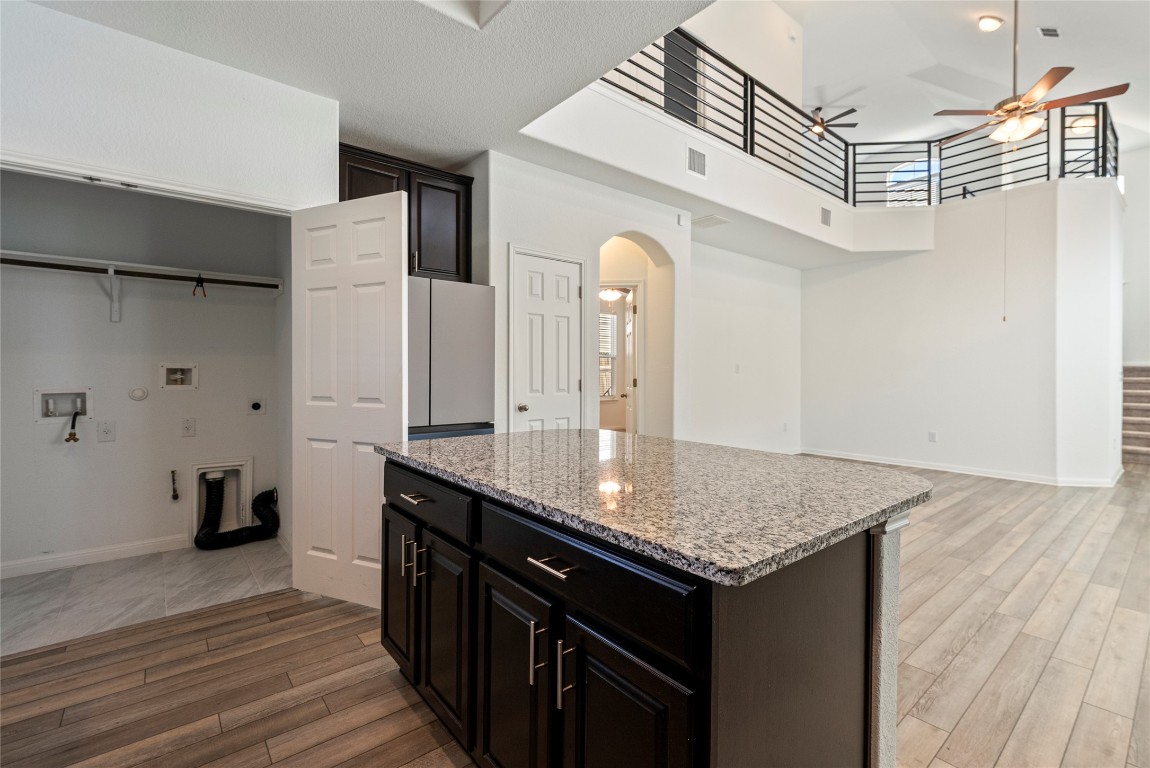 10704 Sentinel Drive Austin, TX 78747 - Photo 22 of 22 Kitchen featuring a kitchen island, arched walkways, open floor plan, light wood-style flooring, and a high ceiling