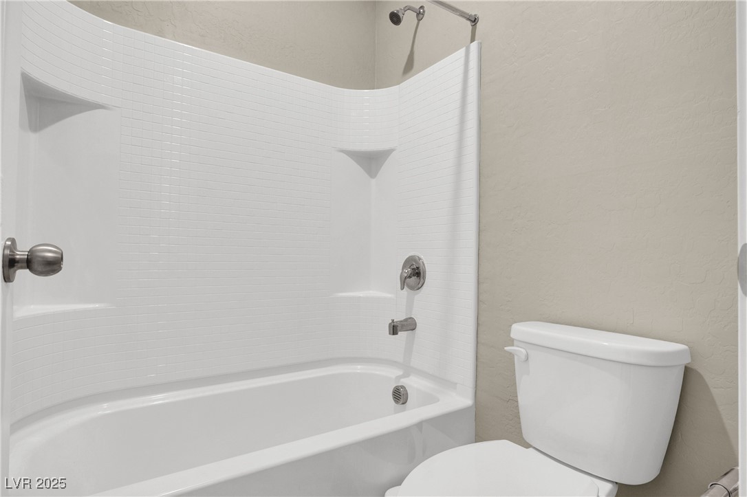 10976 Bluebell Basin Road Las Vegas, NV 89179 - Photo 30 of 40 Full bath featuring a textured wall, toilet, and shower / tub combination