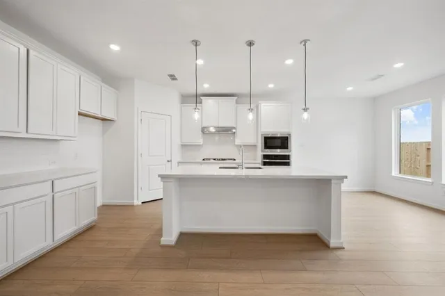 a kitchen with stainless steel appliances granite countertop a sink a stove and a wooden floors
