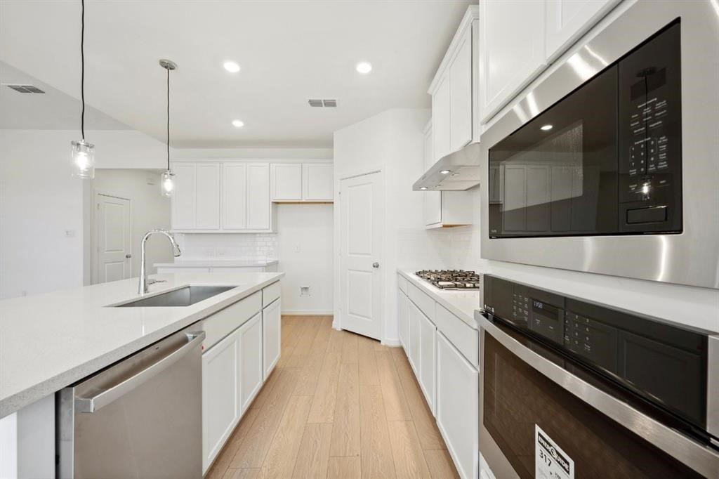 21918 Wycombe Terrace Way Cypress, TX 77433 - Photo 4 of 43 a kitchen with stainless steel appliances granite countertop a sink a stove and a wooden floors