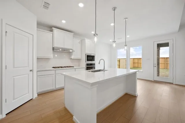 a large kitchen with granite countertop a large counter top a sink stainless steel appliances and cabinets