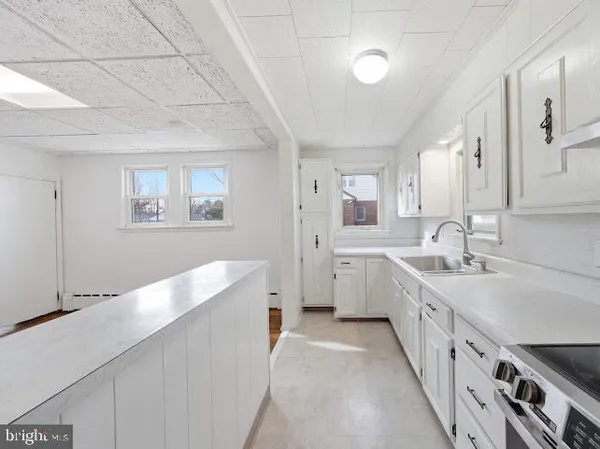 a large white kitchen with stainless steel appliances granite countertop a lot of counter space and wooden floors