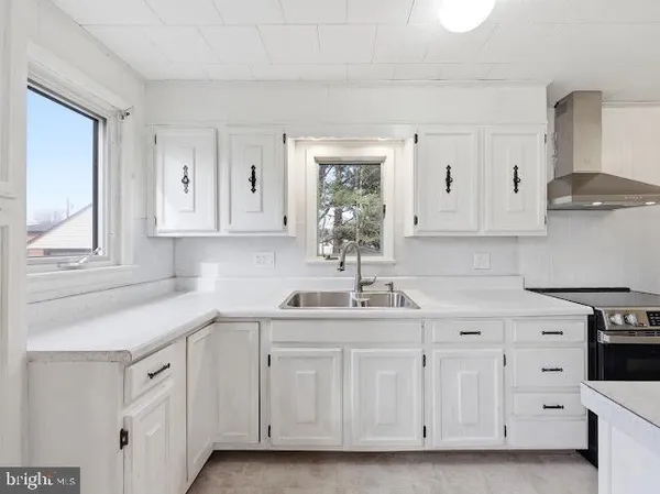 a kitchen with white cabinets white stainless steel appliances and sink