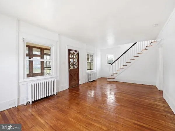 a view of an empty room with wooden floor and stairs