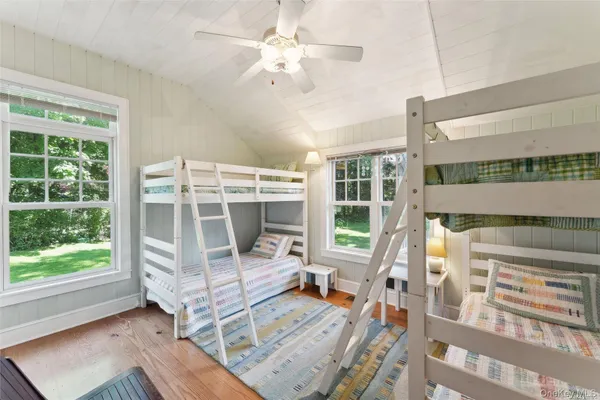 a bedroom with furniture large windows and wooden floor