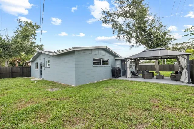 a view of a house with a yard and large tree