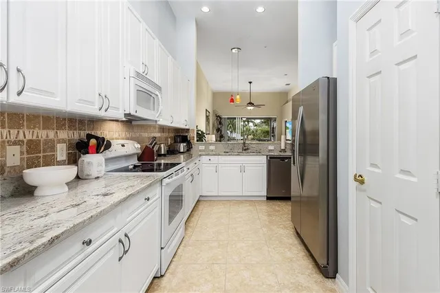 a kitchen with stainless steel appliances granite countertop a sink refrigerator and cabinets
