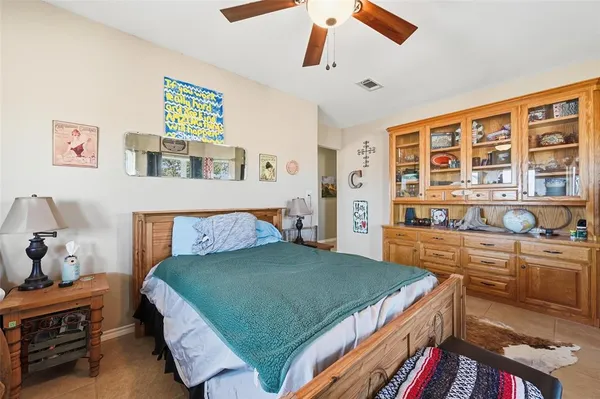a bedroom with a bed a dresser and potted plants on the dresser