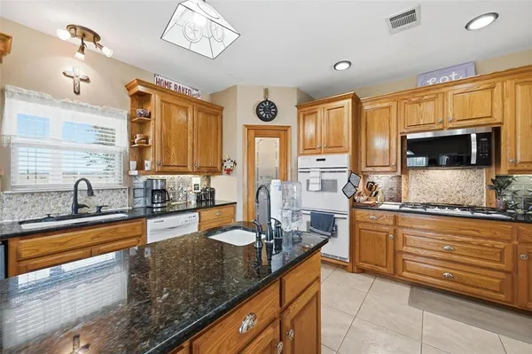 a large kitchen with granite countertop a sink counter space stainless steel appliances and cabinets