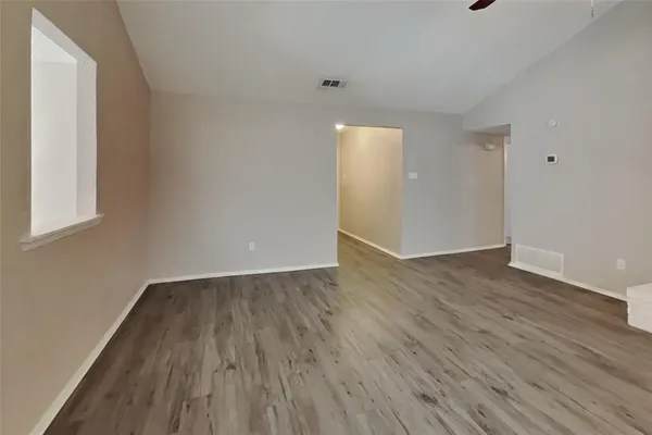 a view of an empty room with wooden floor and a window