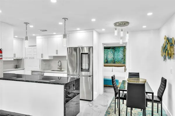 a kitchen with stainless steel appliances granite countertop a refrigerator a sink a stove a dining table and chairs