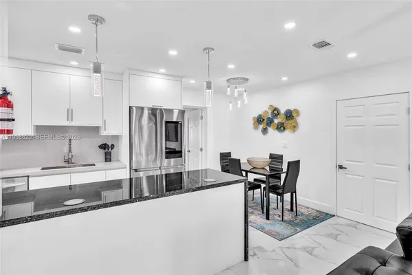 a kitchen with stainless steel appliances kitchen island granite countertop a table and chairs in it