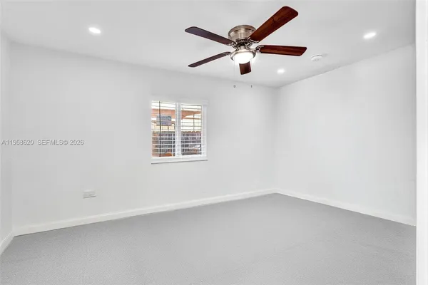 an empty room with a window and ceiling fan
