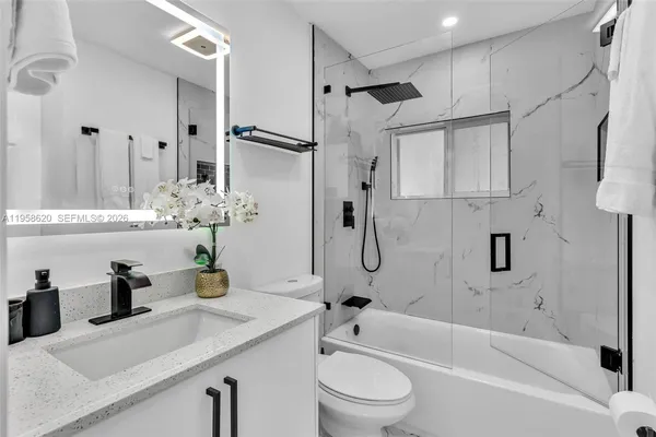 a bathroom with a granite countertop sink mirror toilet and bathtub